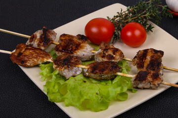 Pork kebab skewers in the plate with salad leaves and tomatoes