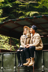 A beautiful girl and a handsome man in military truck. Lovestory. Military vehicle. Military fashion.Carpathian mountains