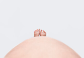 Feet under a pregnant woman belly