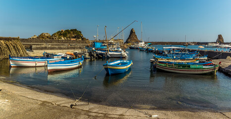 Fototapeta na wymiar A panorama view of Fishermen's boats against a background of Isole dei Ciclopi at Aci Trezza, Sicily in summer
