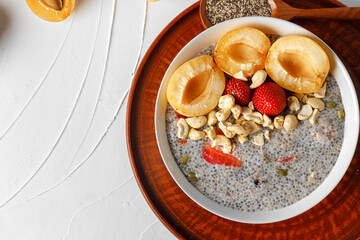 Bowl of chia poudding with pieces of apricots and strawberry
