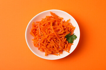 Bowl with tasty carrot salad on orange background, top view