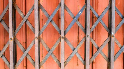 Abstract texture background of closeup red & orange stainless steel or metal folding door of old house in vintage & retro style, home interior & exterior design wallpaper, industrial concept banner