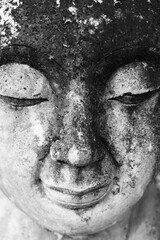 Close up of Buddha face for house interior decor, black & white monochrome. Abstract texture background of eyes closed statue with old grunge & rustic surface, zen spa & spiritual meditation concept 