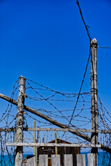 Filo spinato attorcigliato a bastoni di legno usurati su fondo cielo