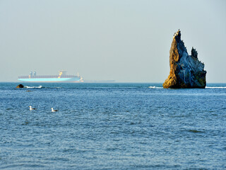 container ship and stone cliff at sea