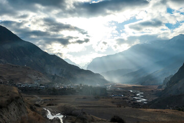 An early morning in Manang Valley, Annapurna Circuit, Nepal. The sun get up above high Himalayan peaks. There is a small village in the middle and a small torrent. Serenity and calmness. New beginning