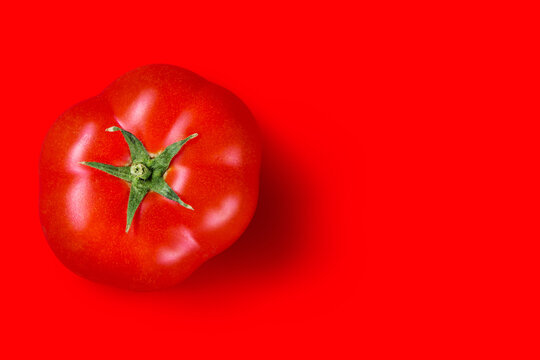 red ripe tomato on a red background, top view, concept