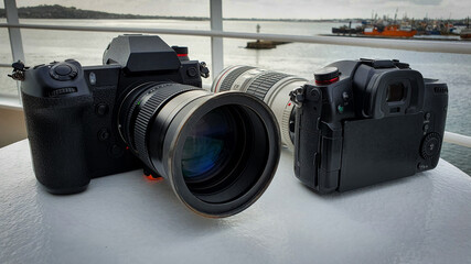 Two black cameras on a boat with docks in background