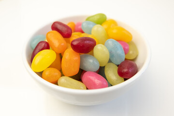 Colorful jelly beans in white bowl, shallow depth of field.
