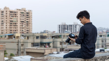 Fototapeta na wymiar Young photographer clicking photographs at terrace during world pandemic. Solo Explorer.