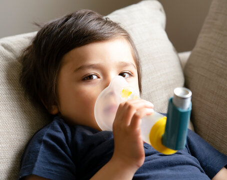 Poor boy have a problem with chest coughing holding inhaler mask, Child using the volumtic for breathing treatment, Kid having asthma allergy using the asthma inhaler, Healthcare and medicine concept - Powered by Adobe