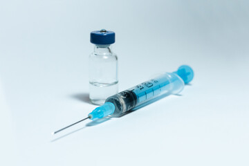 Glass medicine bottle with injection fluid with blue aluminium cap and syringe for vaccination. Cancer, painand diabetes treatment, pharmaceutical medicine concept .