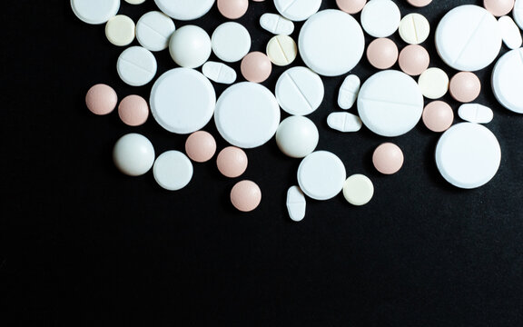Heap of pills, tablets, capsules on black background. Drug prescription for treatment medication health care concept wth copy space background. © Inna