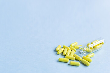 Yellow capsules are poured out of a bottle on a blue background. Omega-3 vitamins. food Supplement. Fish oil in capsules. Free space. copy space. space for text. blurred background. Selective focus.
