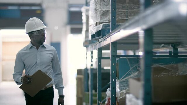 A confident warehouse manager looks over inventory and logistics for an ecommerce facility. Back to work and business is booming. Shot in 4k 