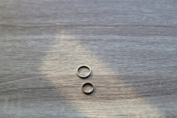 Gold wedding rings on wooden background, illuminated by sunlight. Selective focus.