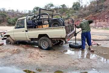 Lifting an off-road car with a Jack made of viscous sandy soil. © okyela
