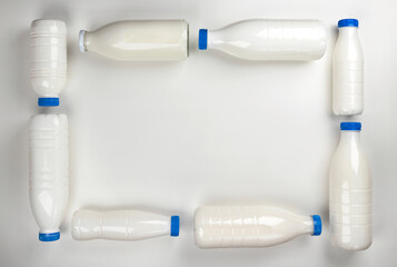 Frame made of bottles for milk and yogurt on white background, top view