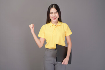 young confident beautiful woman wearing yellow shirt is holding documents on grey background studio