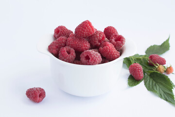 Raspberry in the white bowl on the white background. Closeup.