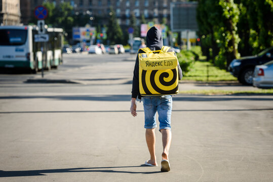 Russia, Saint Petersburg, June 26, 2020: Courier boy in an empty city with a bag "Yandex Food" on his back, view from the back