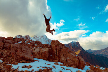 Victorious Young Man Leaping On Epic Mountain Peak Success Concept