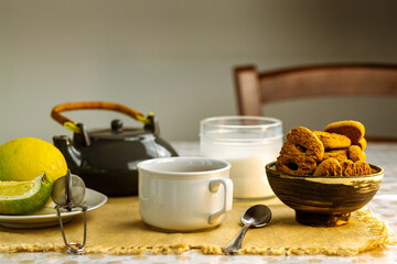 Taza de té negro con azúcar, limones y galletas en el fondo de la mesa rústica
