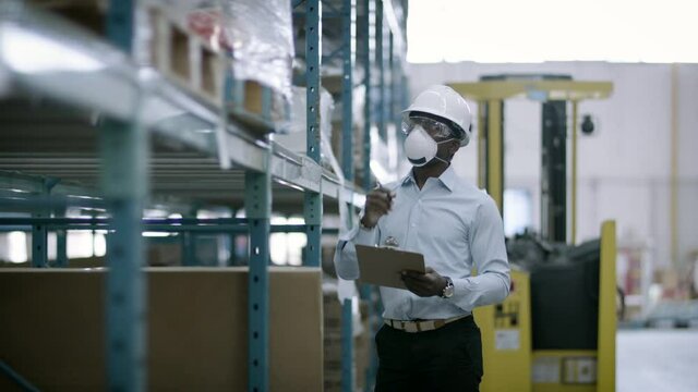 Examining inventory in a mask. A manager checks warehouse safety and inventory. Shot in 4k 