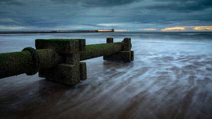 Disused wast pipe on Blyth Beach, Northumberland, England, UK. On overcast morning at dawn, with incoming waves. 