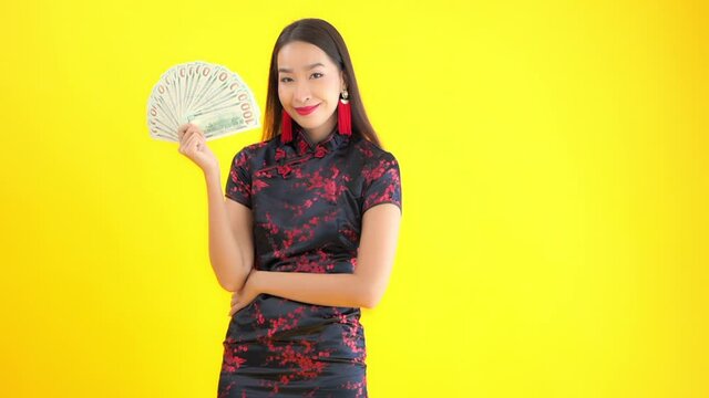 Holding a fan full of one hundred dollar bills, an attractive young woman keeps her self cool. Copy space