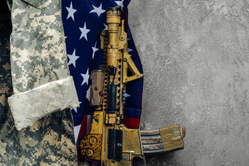 U.S. battle flag and assault rifle near the wall. close up.