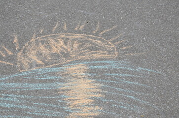 Children's drawing with colorful chalk on the asphalt sun.