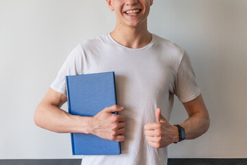 Happy smiling student with diploma thesis. Young man with thumb up