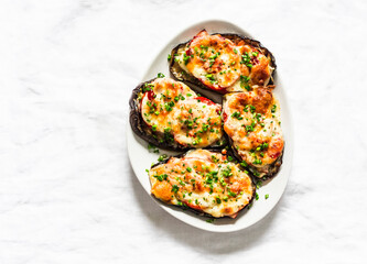 Roasted eggplant steak with ham, tomatoes and mozzarella cheese - delicious appetizer, tapas on a light background, top view