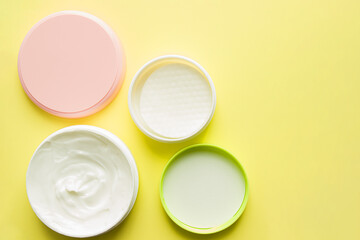 Cosmetics and hygiene products for skin care. Set of face and body care products-top view, on a yellow background, beauty concept. Cosmetic cream for body care in a round package.