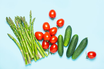 Fresh vegetables on a blue background. Crops. Asparagus, tomatoes, cucumbers. Flat lay. The concept of proper nutrition.