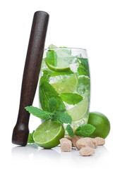 Glass of Mojito summer alcoholic cocktail with ice cubes mint and lime on white with cane sugar and raw lime with wooden muddler