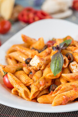 Penne pasta in tomato sauce with chicken, tomatoes decorated with parsley