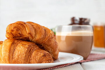 Tasty croissant with cup of coffee with milk on kitchen table