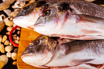 pesce sul tagliere con conchiglie e sfondo in legno