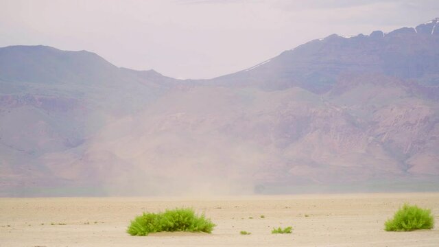 Dust devil blows across a dried up lake bed in a lifeless area.