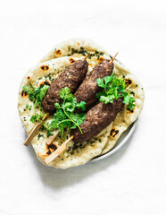 Grilled kebab and garlic herb flatbread naan on a light background, top view. Delicious tapas