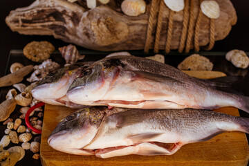 pesce sul tagliere con conchiglie e sfondo in legno