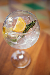 Gin and tonic with rosemary on wooden table, sunny weather. Gin tonic in sunny summer day