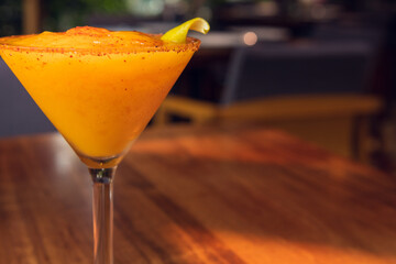 Mango margarita frappe on wooden table, sunny weather. Daisy in summer.