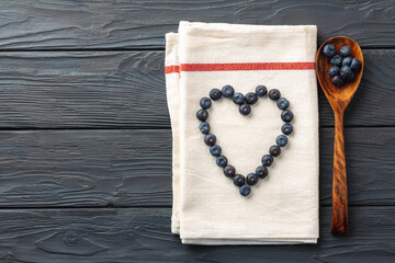 Top view of fresh blueberries shaped in heart on cotton napkin
