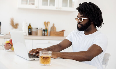 Fototapeta na wymiar Young black man working at home with laptop