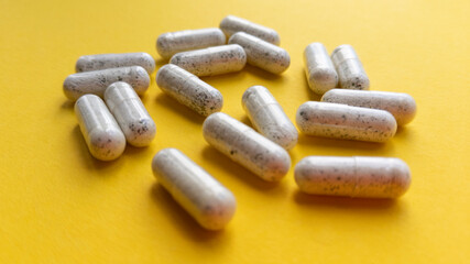 White pill capsules on yellow background. Simple flat lay with pastel texture. Medical concept. Stock photo.