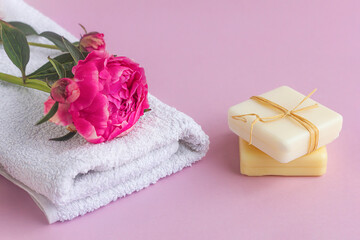 Obraz na płótnie Canvas Natural soap with peony extract, floral scent and towel. Face and body skin care, natural cosmetics, spa treatments on pink background